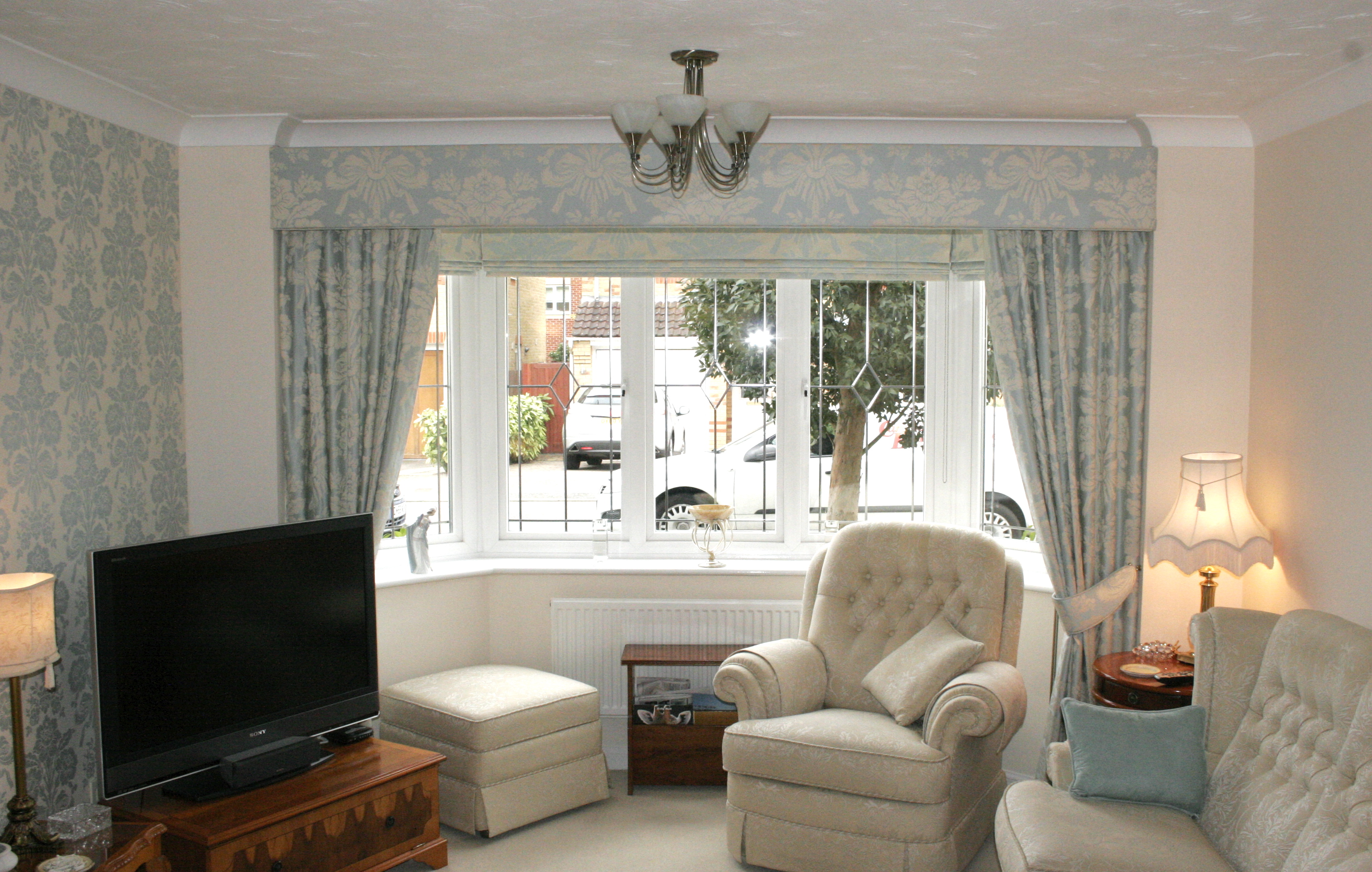 Roman blinds around bay window with dress curtains, tie backs and pelmet in customers own fabric. Bishops Stortford  - Soft furnishings -  Carolina Blinds